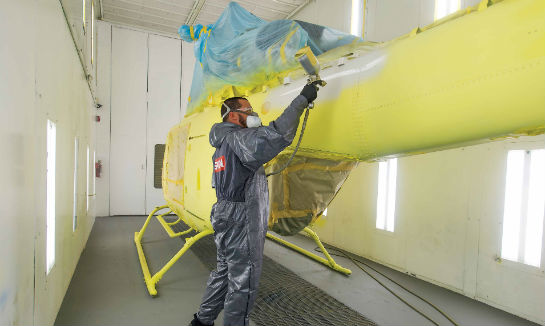 Inside the paint booth, Xavier Quiñonez sprays a primer coat on a new Bell 429.