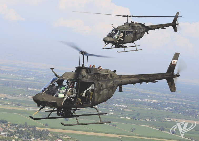 Two of the latest MEP (mission equipment package) versions of the OH-58A+ fly in formation during a transit to an operational area. Flights with the doors removed are typical for Team Eagle units, as it provides better visibility and keep crews cooler during the hot summer months.