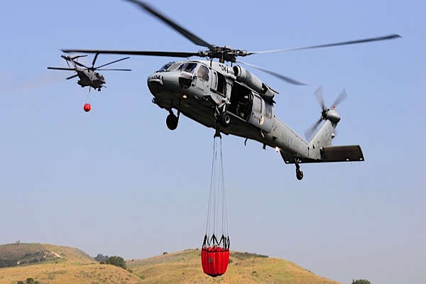 Since May 2008, MCIW, 3rd MAW and Navy Region Southwest have coordinated to conduct an annual wildland fire exercise to prepare for Californias fire season. Here, an HSC-3 MH-60S passes by an HMH-465 CH-53E during a bucketing demonstration.