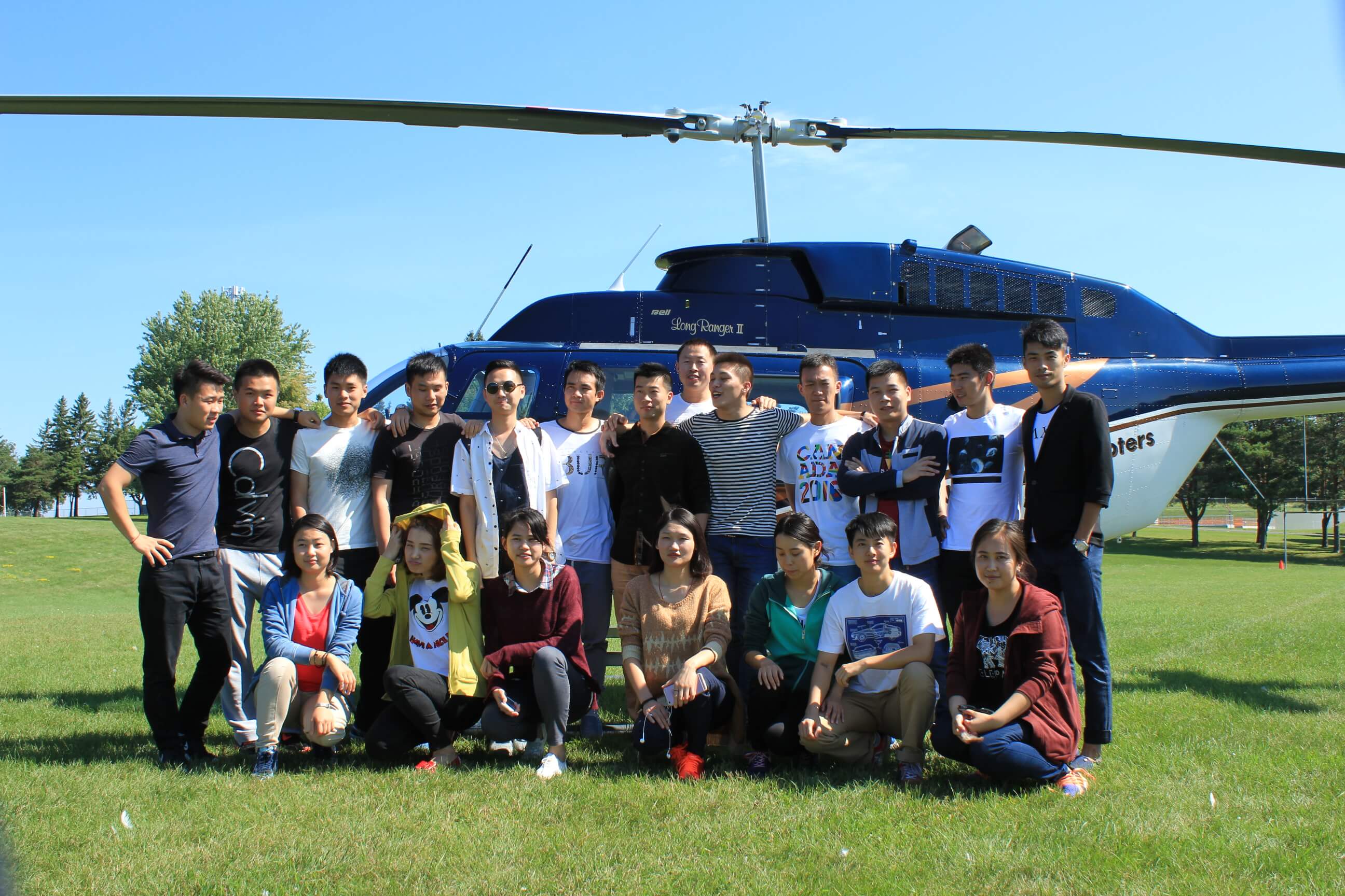 Chinese students pose in front of helicopter.