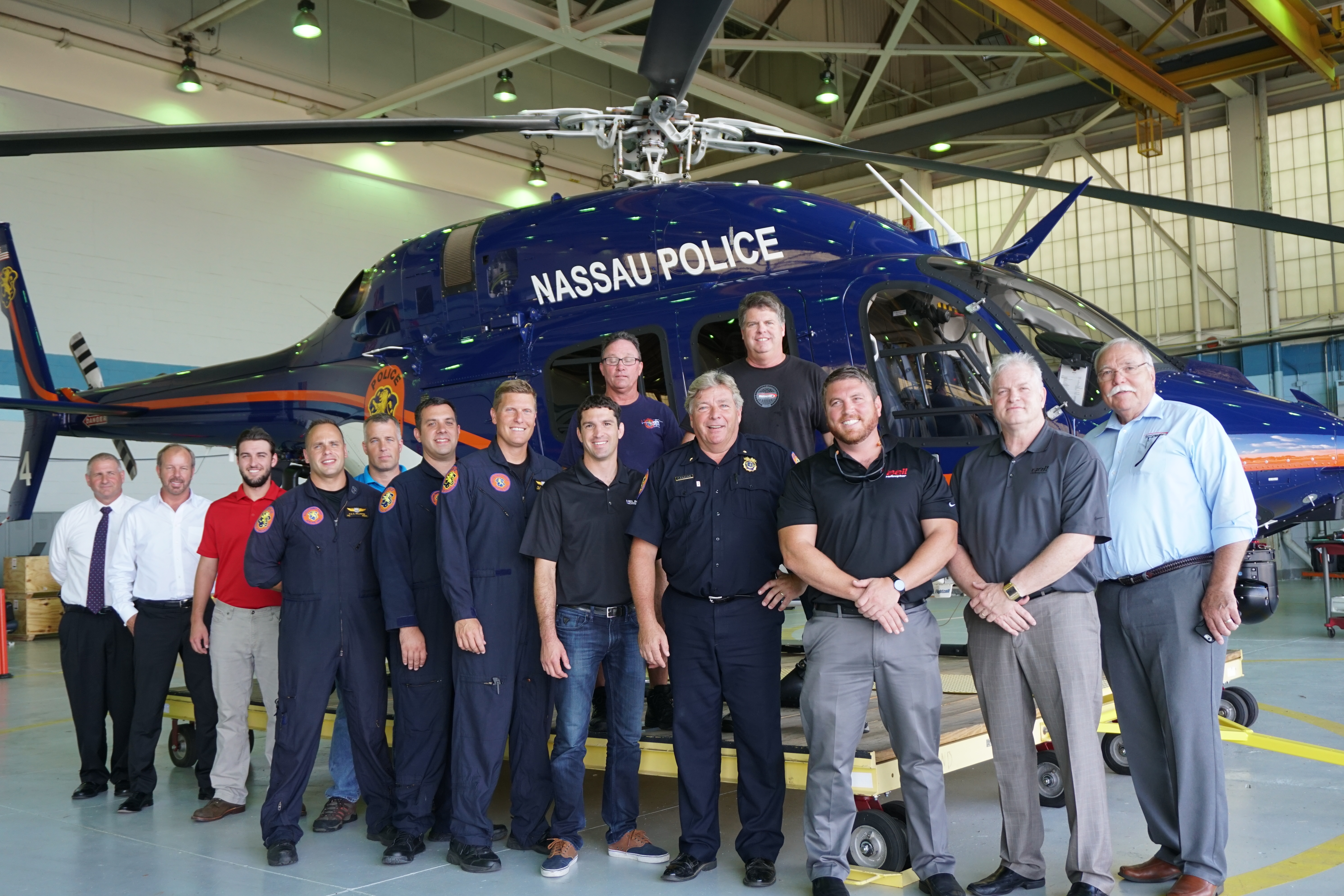 A group of people stands in front of a Nassau Police helicopter