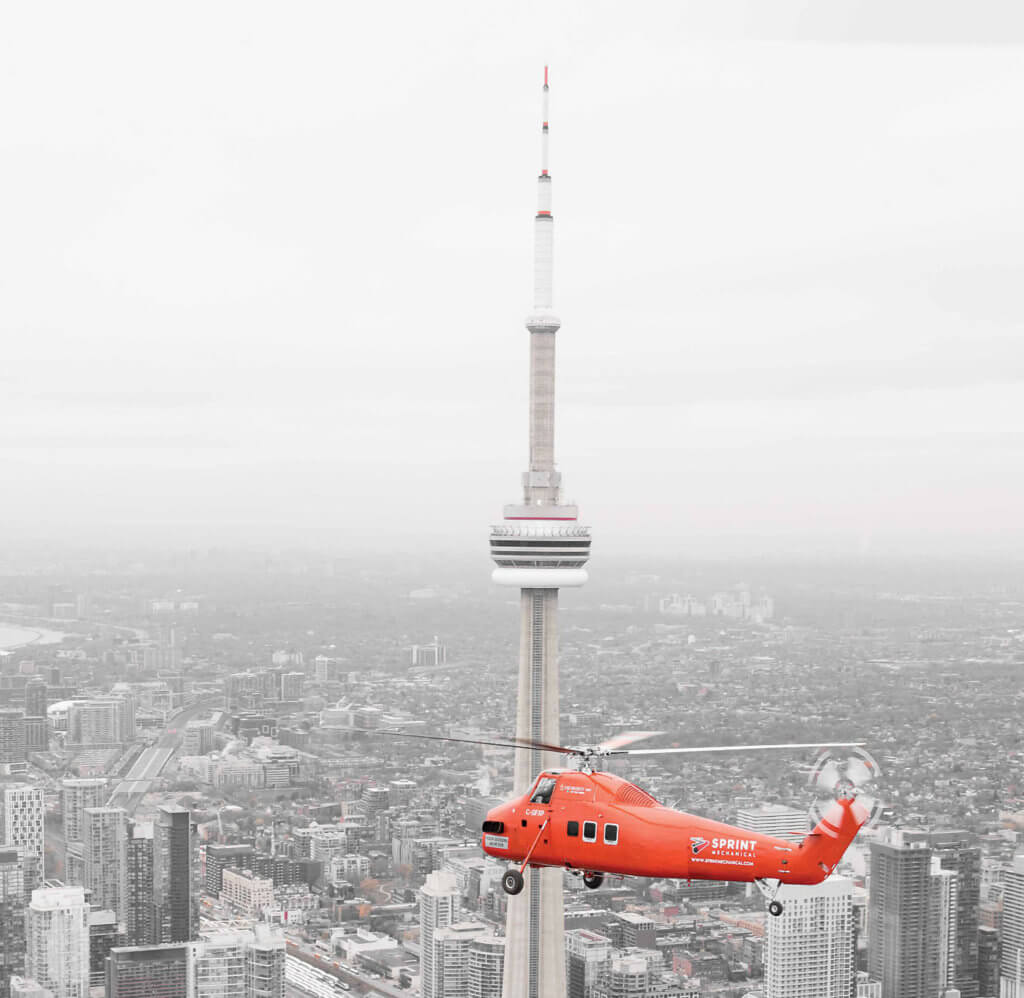 The S-58ET flies above the iconic skyline of downtown Toronto, with the CN Tower and Rogers Centre in the background. The aircraft is the only one of its type currently flying in Canada.