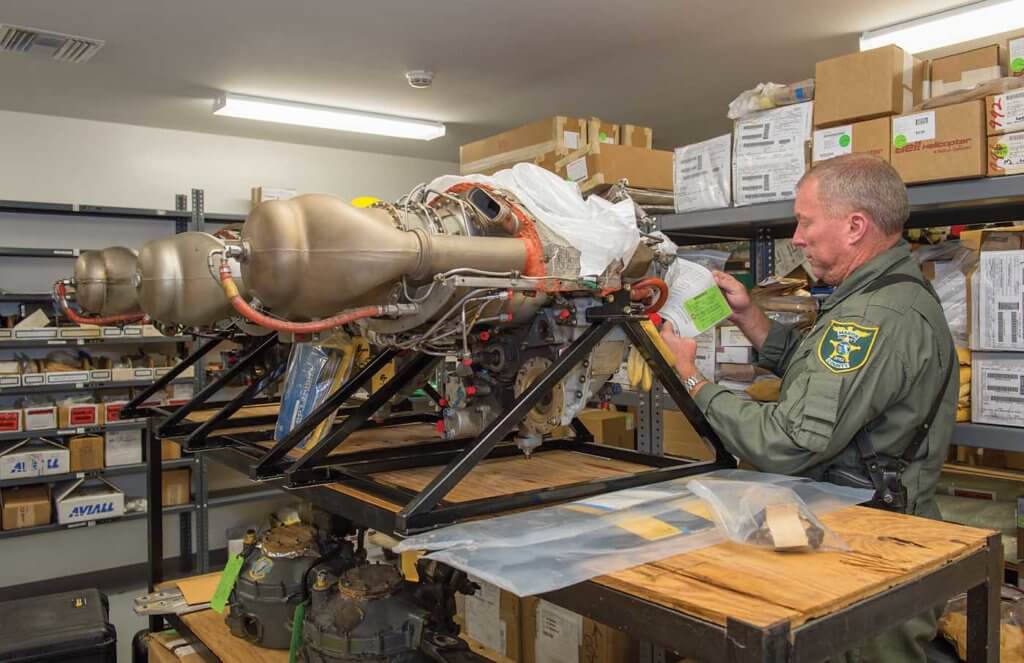 Chief Pilot, Deputy Sheriff Doug Newsom, inspecting tags and paperwork on some of the unit's extensive parts inventory.