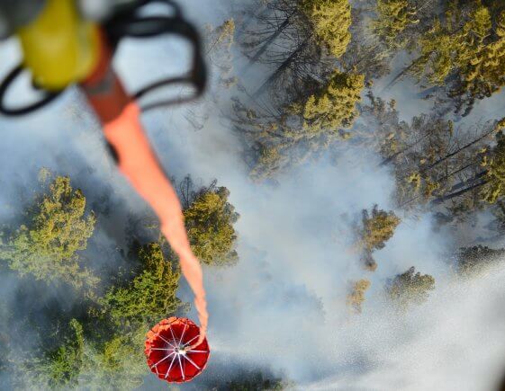 An Oregon Army National Guard CH-47 Chinook helicopter with 1st Battalion, 168th Aviation Regiment dups a 2,000 gallon capacity Bambi Bucket amid smoke over the Mt. Jefferson Wilderness Area in order to support firefighting efforts on the Whitewater Fire on August 5, 2017.