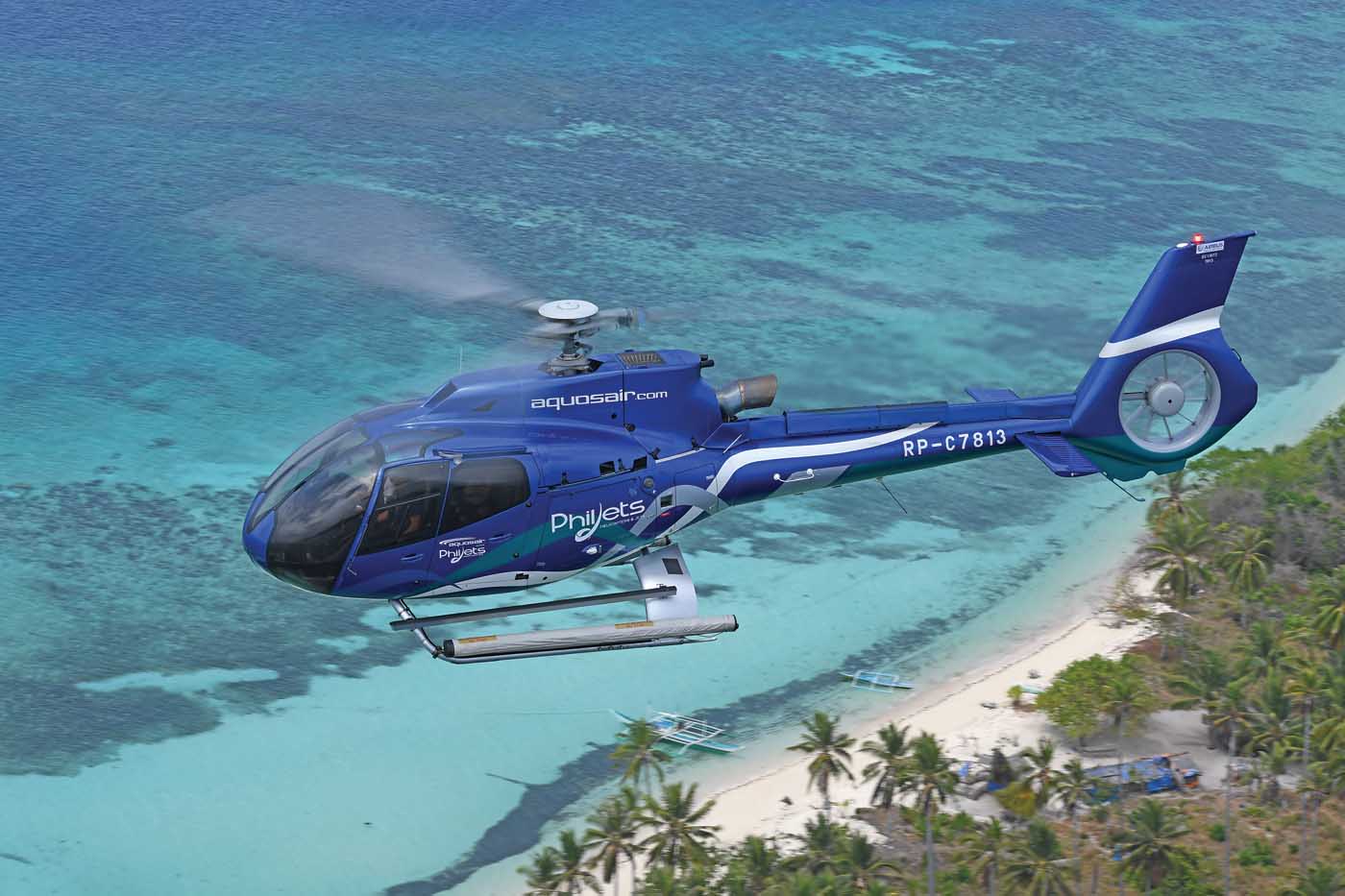A PhilJets Airbus H130 flies over a picture-perfect piece of Philippine coastline.