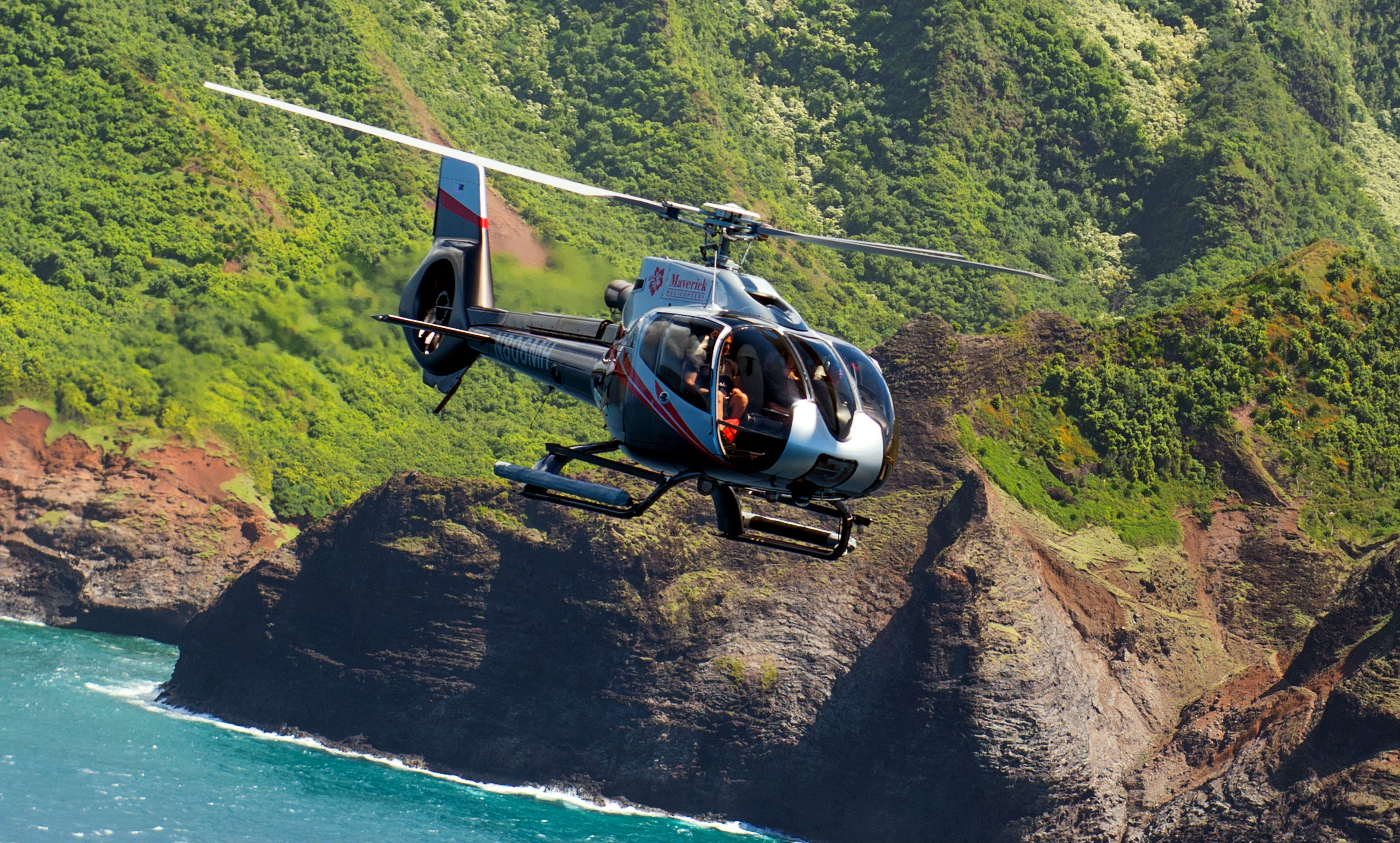 A Maverick Helicopters Airbus EC130 B4 flies along the Hawaiin coastline. Maverick Helicopters Photo