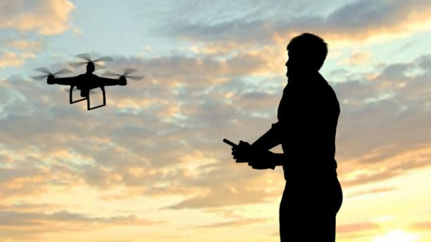man operating of flying drone quadrocopter at sunset.