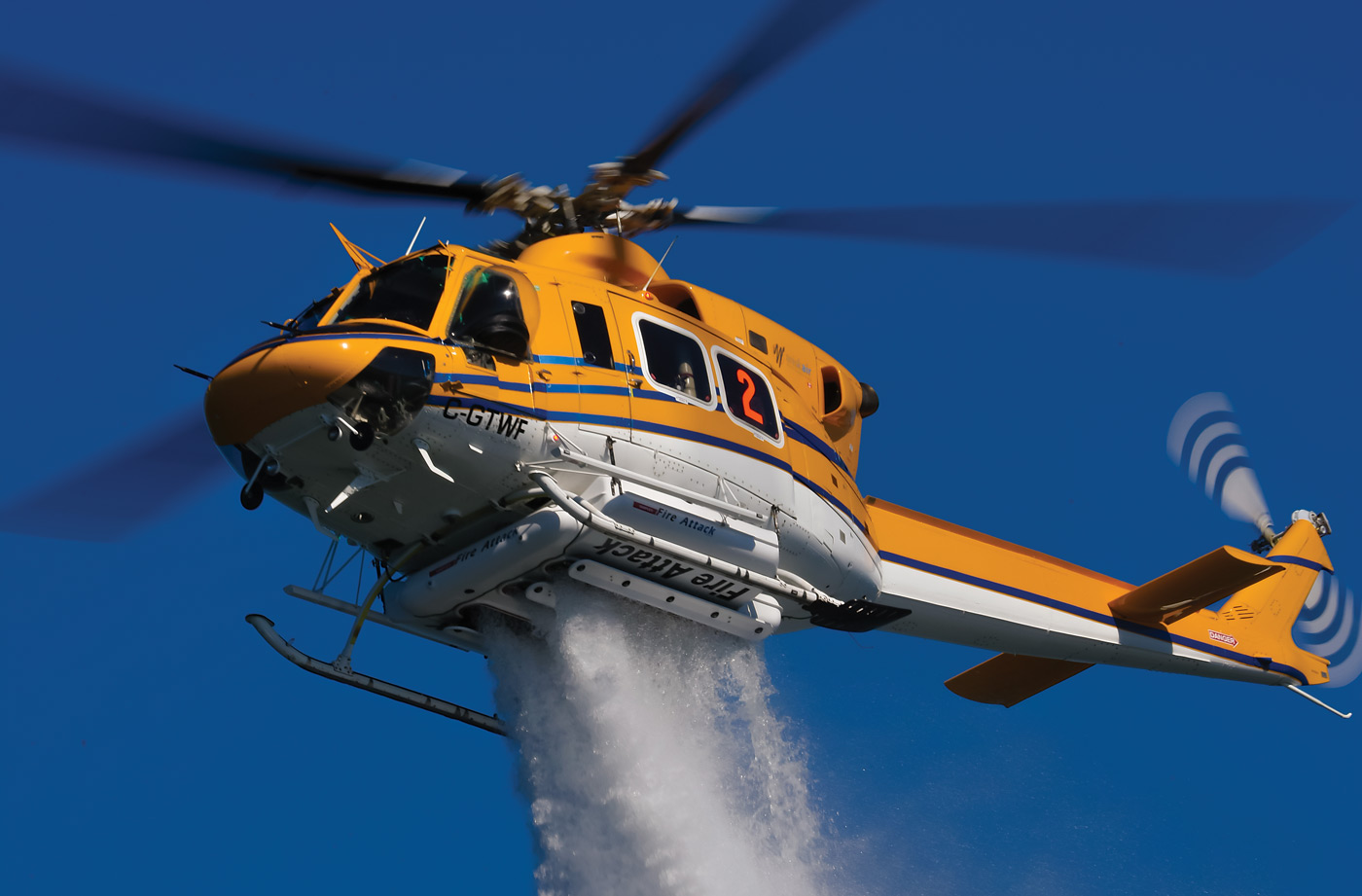 A Bell 412 operated by Wisk Air Helicopters demonstrates a water drop with its 375-gallon (1,420-liter) Simplex Belly Tank. The aircraft is one of three 412s in the operator’s fleet, and is working on a major firefighting contract this summer. Mike Reyno Photo