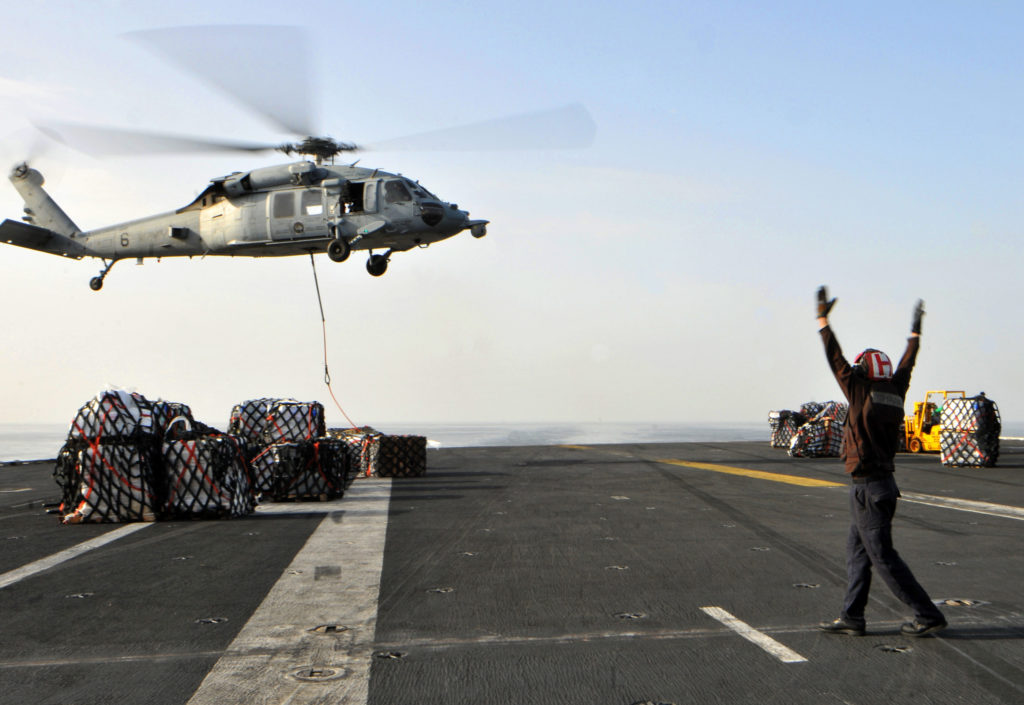 Aviation Structural Mechanic Airman Guilio Marchionne directs an MH-60S Sea Hawk on the flight deck of aircraft carrier USS Abraham Lincoln during a replenishment at sea.  (U.S. Navy photo by Mass Communication Specialist 3rd Class Christina I. Naranjo)