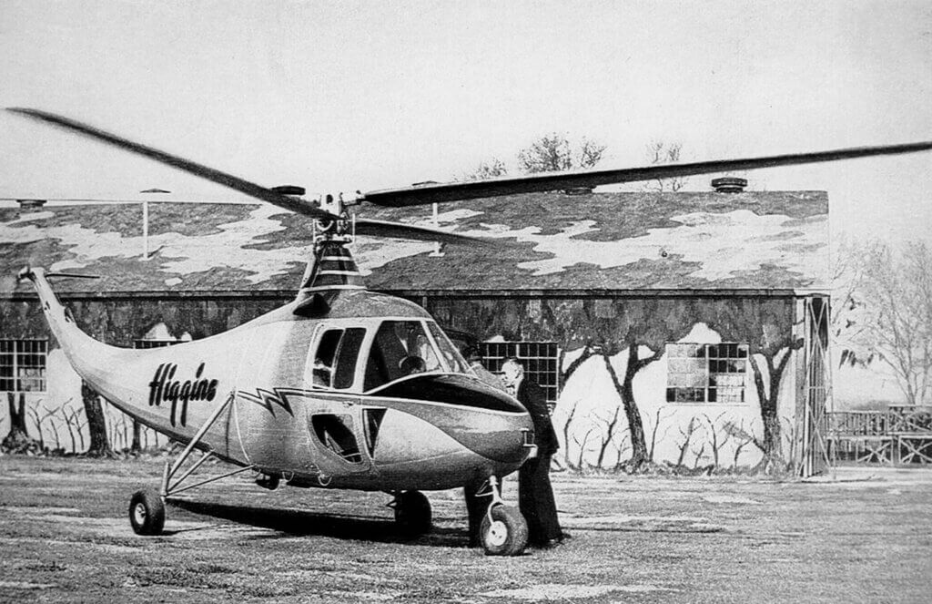 A four-bladed Higgins EB-1 helicopter rests on the ground.
