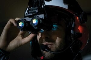Helicopter pilot wearing night vision goggles in the dark.