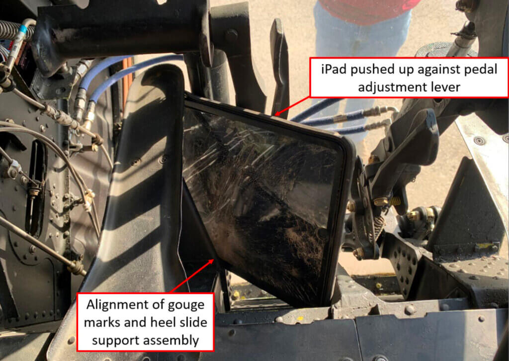 NTSB investigators were able to align gouge marks on the accident flight crew’s iPad with a sharp, vertical metal piece of the co-pilot’s heel slide support assembly. NTSB Photo